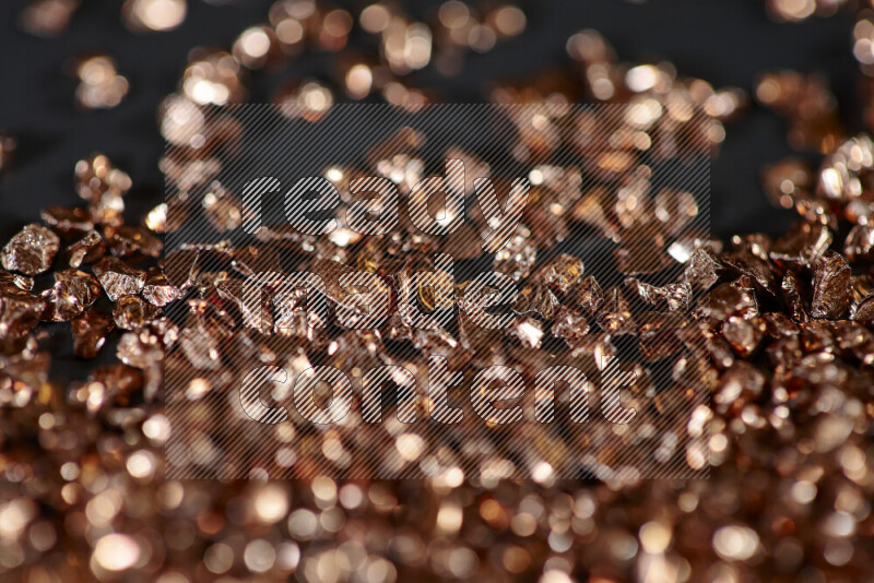 Bronze shimmering fragments of glass scattered on a black background