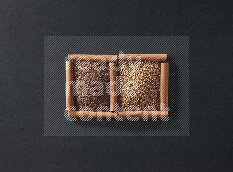 مربعان من أعواد القرفة ممتلئان بحبوب الخردل وبذور الكتان علي خلفية سوداء