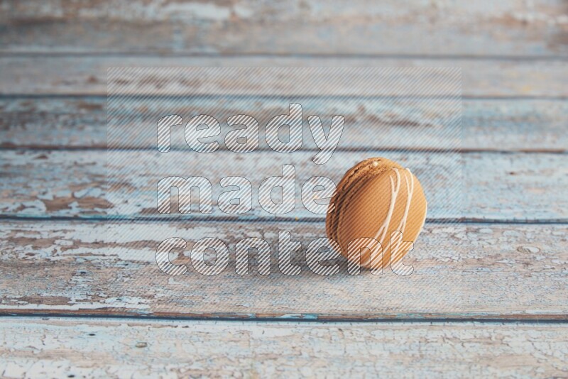 45º Shot of Brown Irish Cream macaron on light blue wooden background