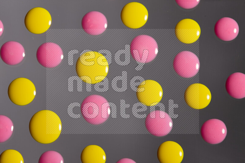 Close-ups of abstract pink and yellow paint droplets on the surface