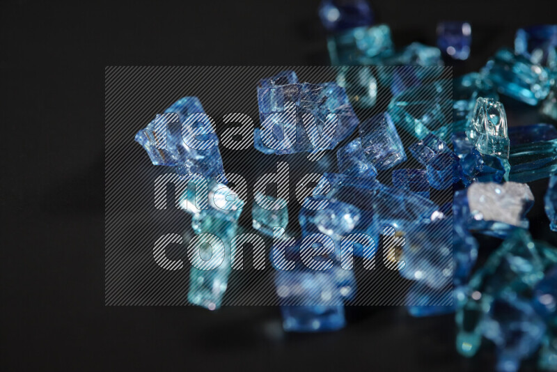 Transparent blue fragments of glass scattered on a black background