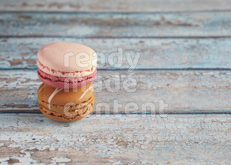 45º Shot of of two assorted Brown Irish Cream, and Pink Litchi Raspberry macarons on light blue background