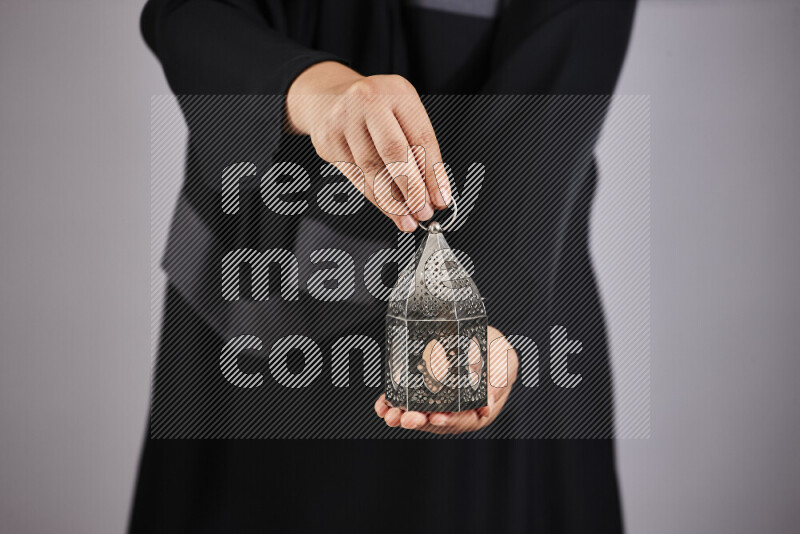 A woman in black abaya holding different ramadan lanterns in different positions