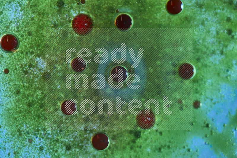 لقطات مقربة لقطرات ألوان مائية حمراء وخضراء على سطح الزيت على خلفية خضراء