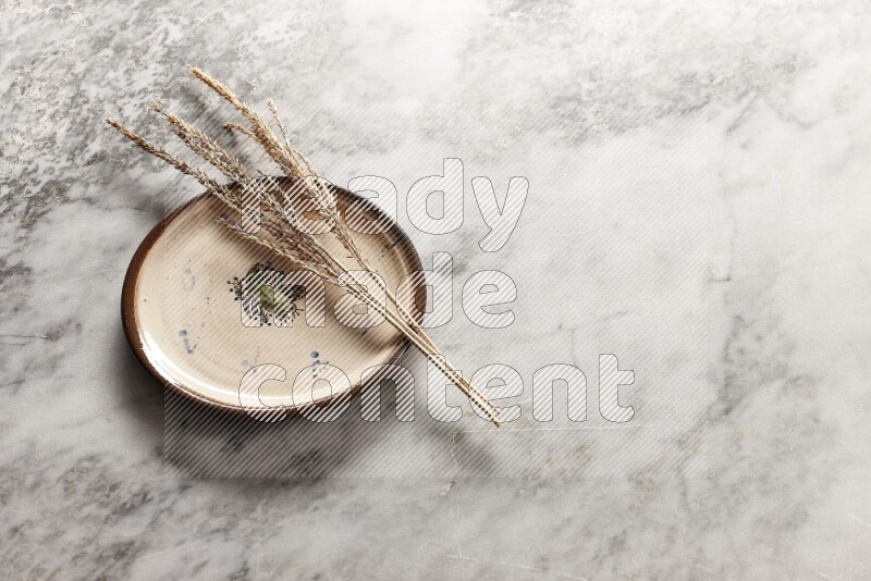 Wheat stalks on decorative pottery plate on grey marble background