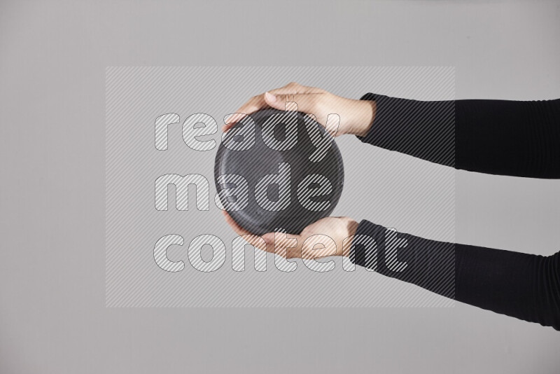 A woman in black abaya holding different pottery essentials in different positions
