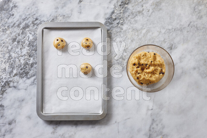 Cookies step by step with its ingredient, flour, butter, brown sugar, egg, vanilla extract, white sugar, chocolate chips and baking soda on grey marble background