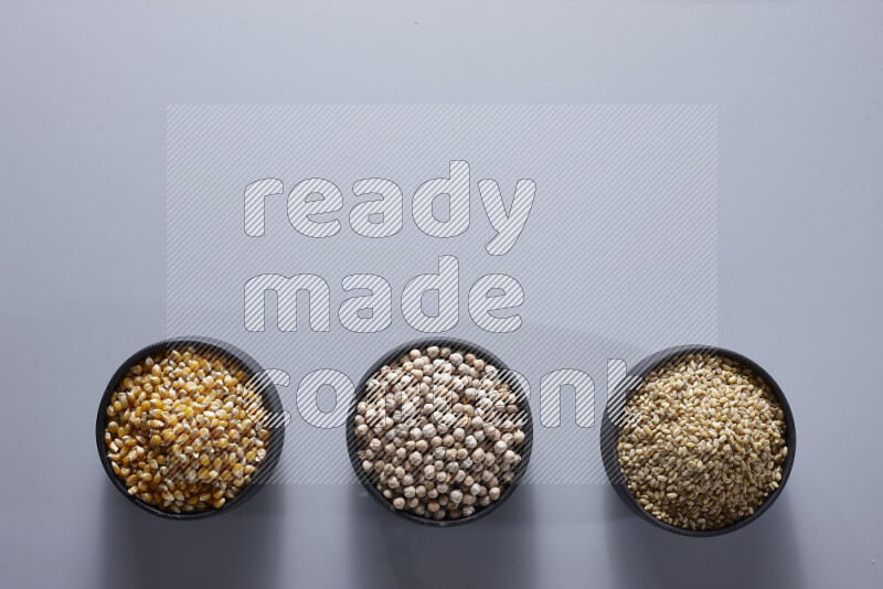 Legumes in pottery bowls on light grey background