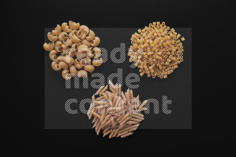 Different pasta types in bunches on black background