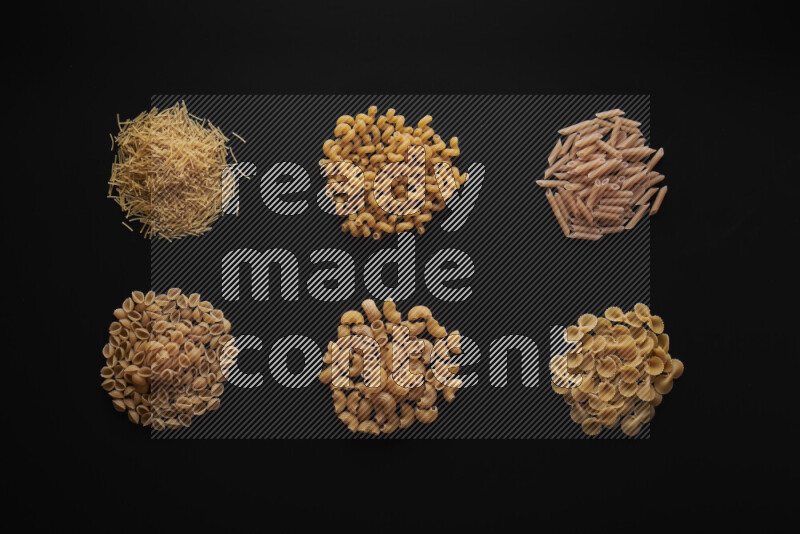 Different pasta types in bunches on black background