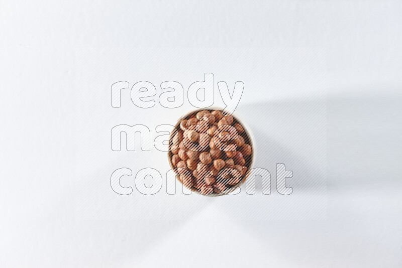 A beige ceramic bowl full of peeled hazelnuts on a white background in different angles