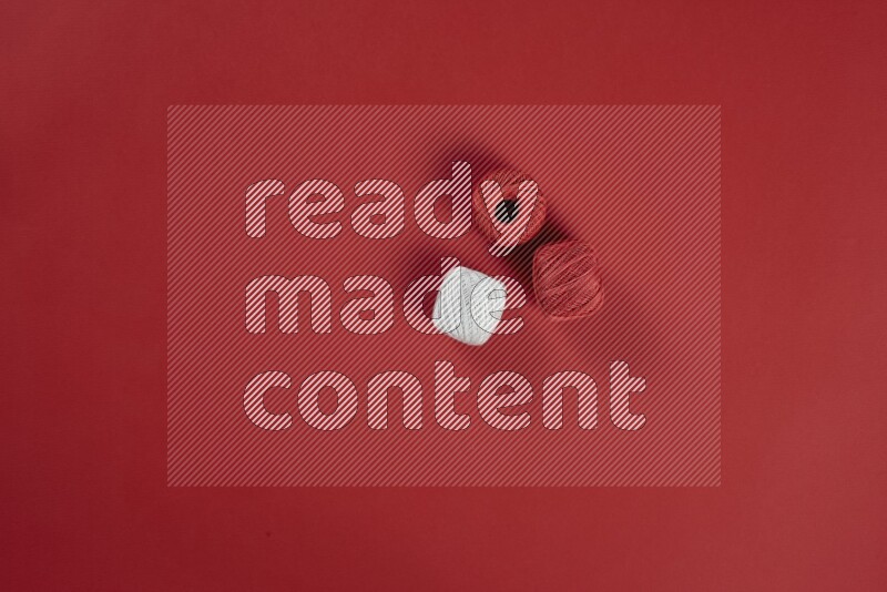 A white collection of sewing and tailoring tools arranged on a red background