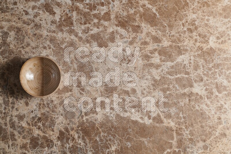 A beige pottery bowl on beige marble background