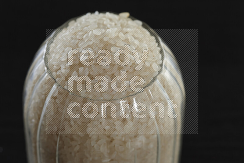 White rice in a glass jar on black background