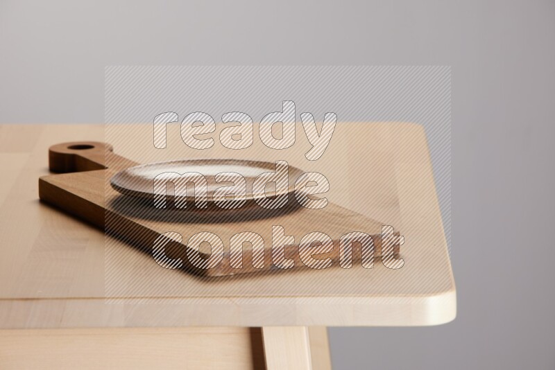 multi-colored pottery Plate placed on a  wooden rectangular cutting board on the edge of wooden table