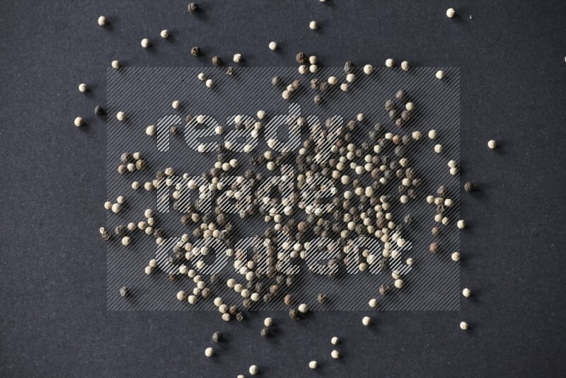 حبوب الفلفل المختلطة السوداء والبيضاء على أرضية سوداء