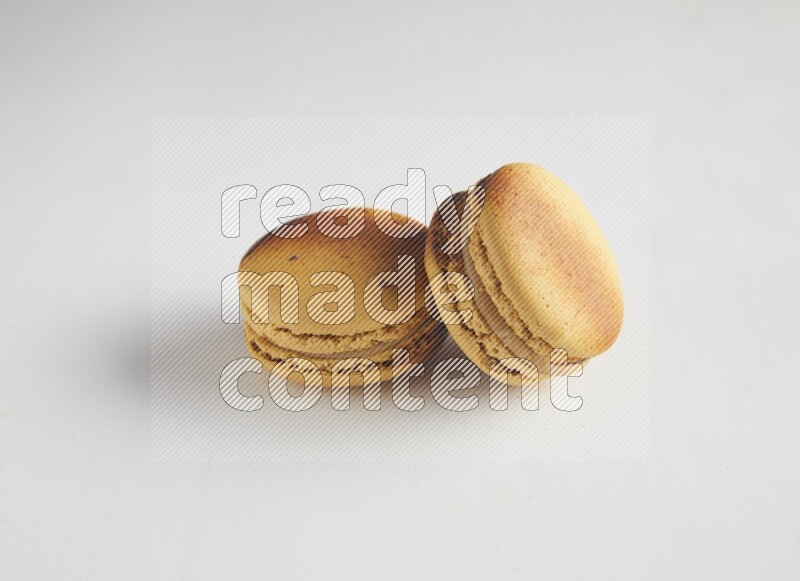 45º Shot of two Yellow Crème Brulée macarons on white background
