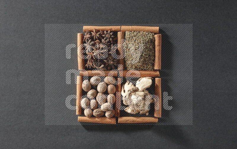 4 squares of cinnamon sticks full of star anise, cumin, dried ginger and nutmegs on black flooring