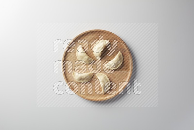 Five Sambosas on a wooden round plate on a white background