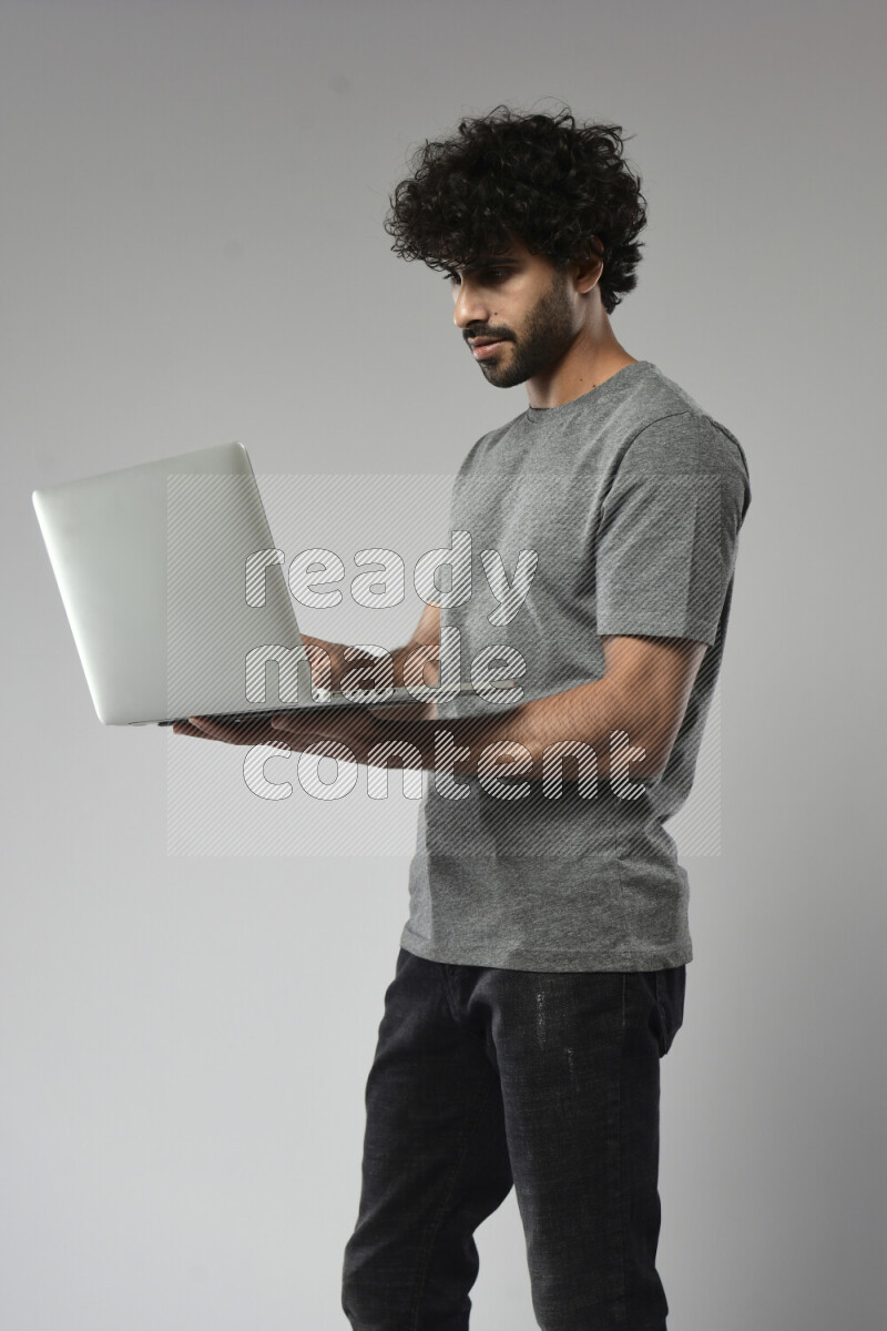 A man wearing casual standing and working on a laptop on white background