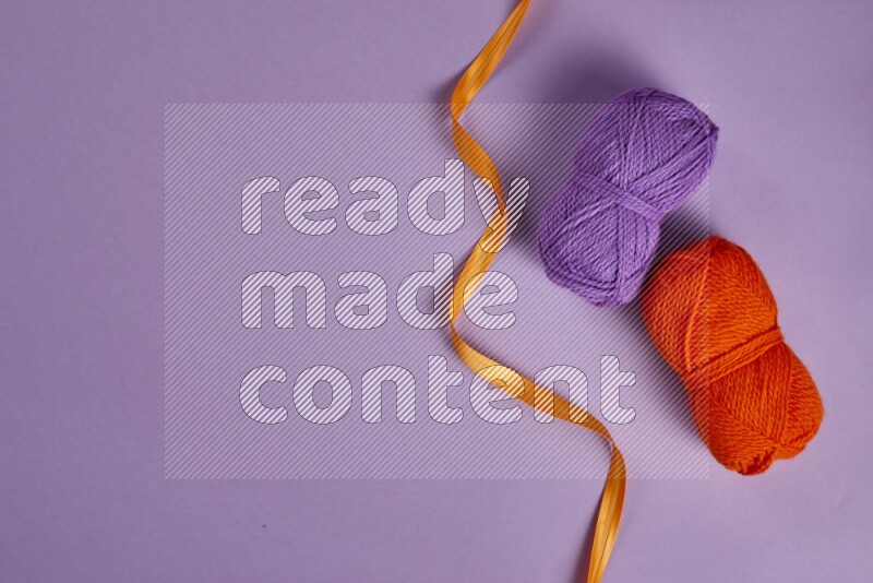 An orange collection of sewing and tailoring tools arranged on a purple background