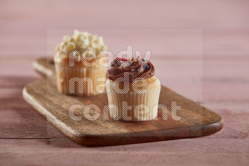 Vanilla mini cupcake topped with chocolate cream on a wooden board