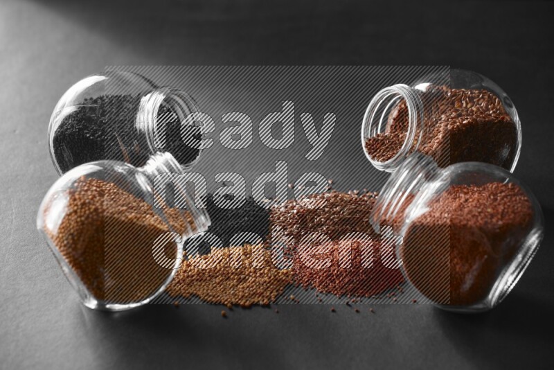 حبة البركة و حبوب الخردل وحبوب الكتان وحب الرشاد في أوعية زجاجية علي خلفية سوداء