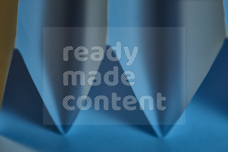 A close-up abstract image showing sharp geometric paper folds in blue gradients