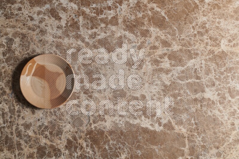 A multicolored pottery plate on beige marble background