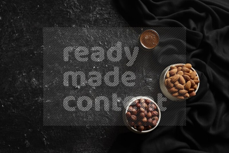 Nuts in pottery bowls with coffee in a dark setup