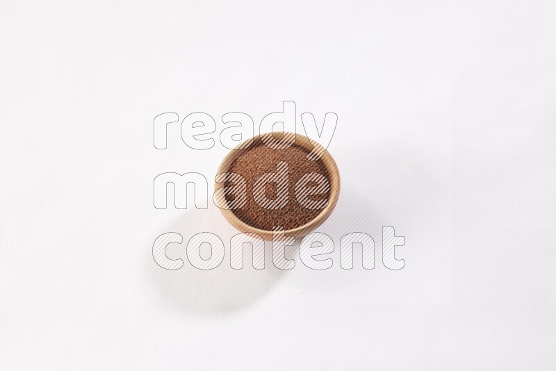 A wooden bowl full of garden cress seeds on a white flooring