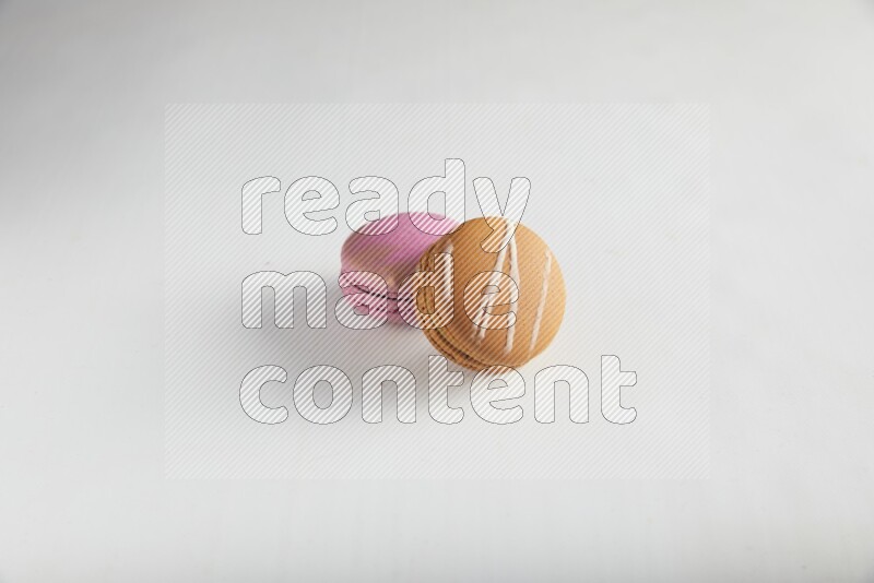45º Shot of of two assorted Brown Irish Cream, and Purple Strawberry macarons on white background