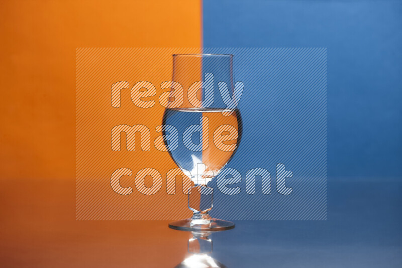 The image features a clear glassware filled with water, set against orange and blue background