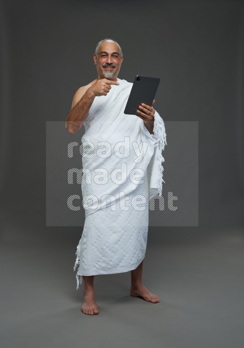 A man wearing Ehram Standing working on tablet on gray background
