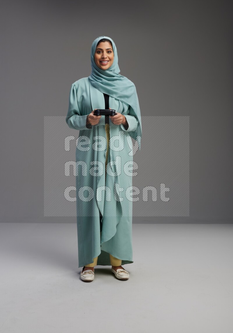 Saudi Woman wearing Abaya standing Playing Games on Gray background