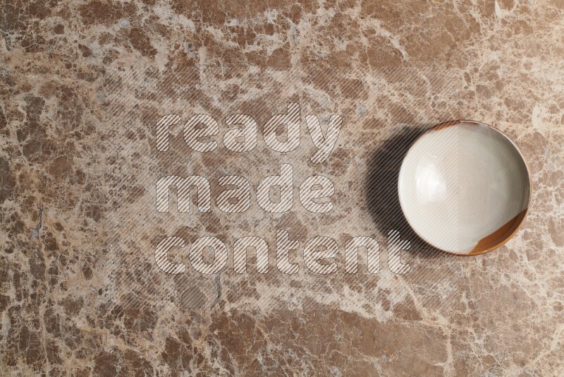A multicolored pottery bowl on beige marble background