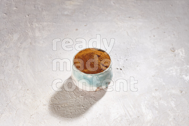 A colored pottery bowl full of ground paprika powder on white background