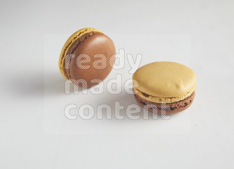 45º Shot of two Yellow and Brown Chai Latte macarons on white background