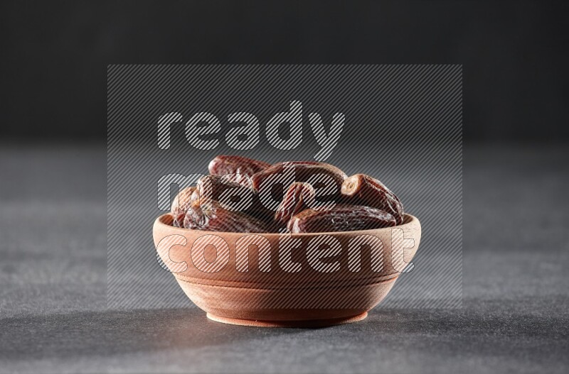 A wooden bowl full of dried dates on a black background in different angles