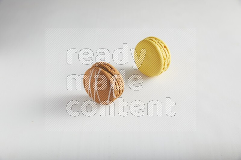 45º Shot of of two assorted Brown Irish Cream, and Yellow Lemon macarons on white background