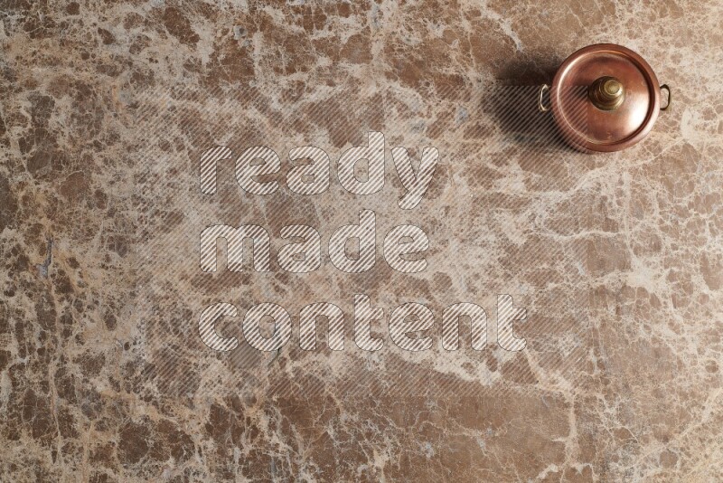 A small copper pot on beige marble background