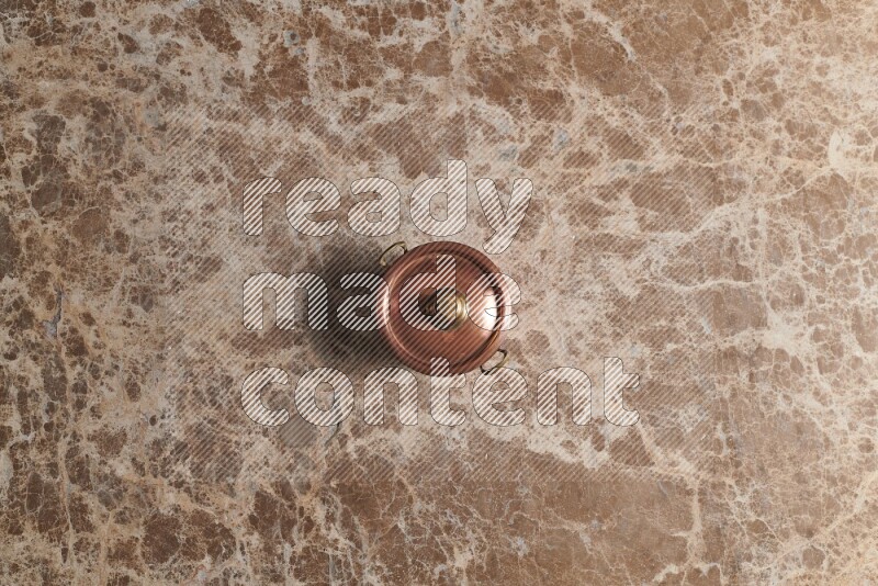 A small copper pot on beige marble background