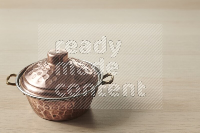 A small copper pot on light wooden background