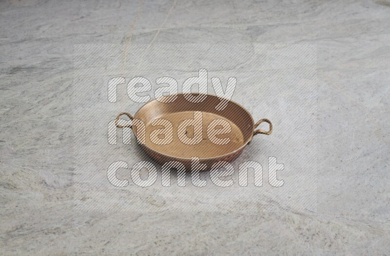 A small copper pan on grey marble background