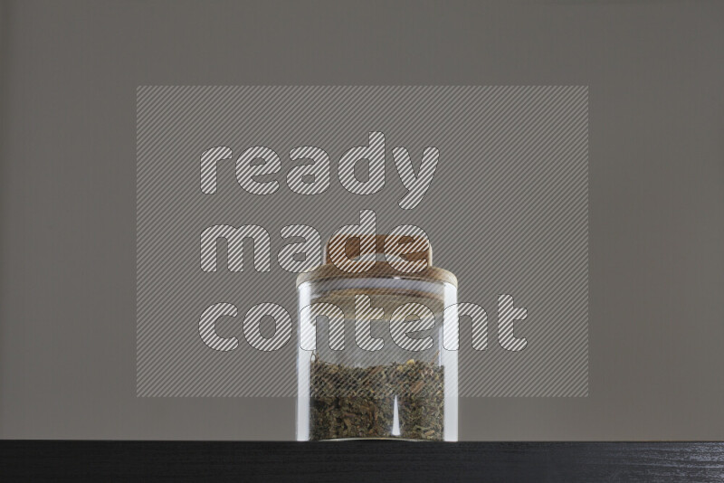 Dried basil in a glass jar on black background