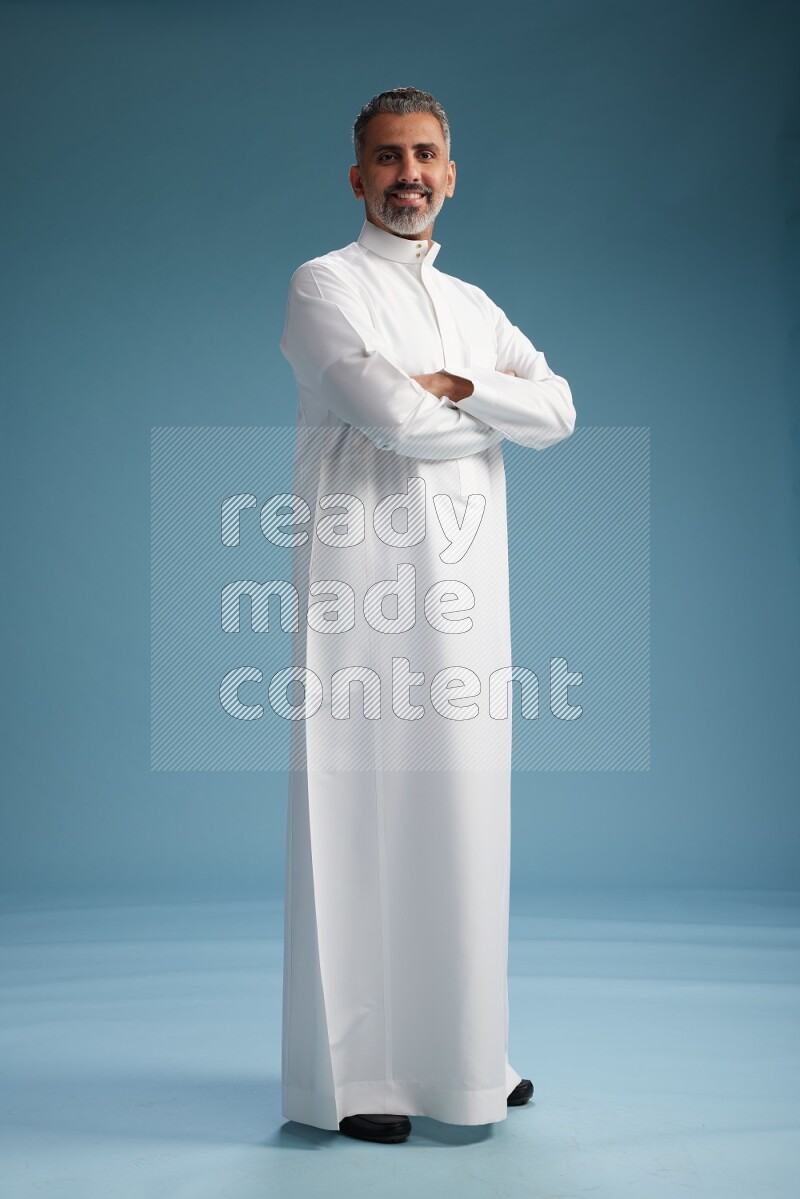 Saudi man waring thob posing to the camera on blue background