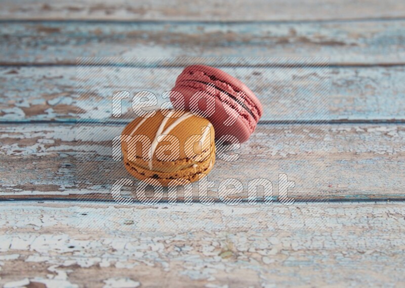 45º Shot of of two assorted Brown Irish Cream, and Pink Raspberry macarons on light blue background