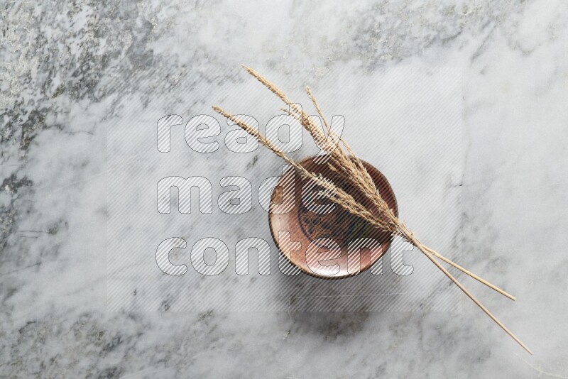 Wheat stalks on decorative pottery plate on grey marble background