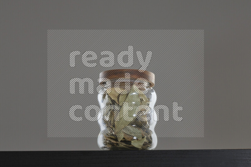 Bay laurel leaves in a glass jar on black background