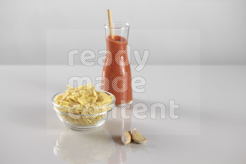 Raw pasta with tomatoe pasta with different ingredients such as cherry tomatoes, basil, garlic, bay laurel, cardamom, white pepper, black pepper, red chilis and wheat stalks on light grey background
